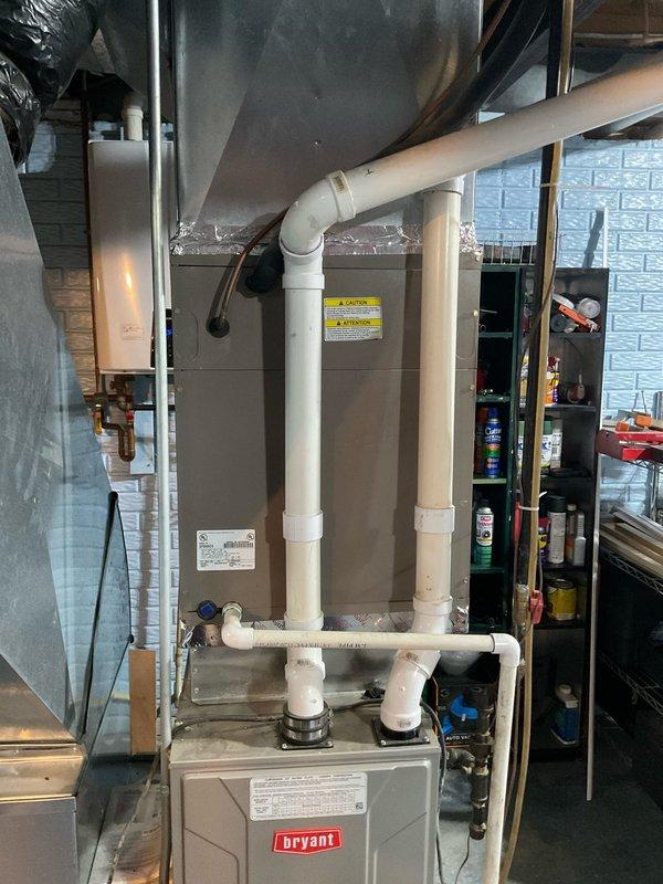Completed comprehensive HVAC system assessment and provided replacement estimate for existing Bryant furnace and air conditioning system. Documented current equipment configuration including vertically stacked components, PVC venting system with pressure monitoring, and associated ductwork in basement utility area. Evaluated installation for replacement specifications covering heating and cooling equipment upgrade requirements.