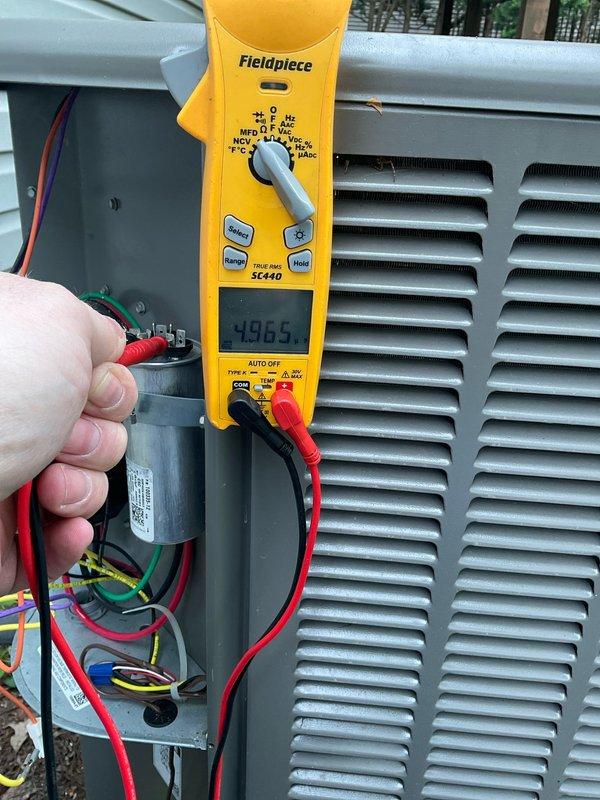 Completed warranty inspection on residential A/C unit. Performed comprehensive system vitals check including visual inspection of outdoor condensing unit and electrical component testing. Verified proper capacitor operation using clamp meter, which displayed normal readings at 49.65 microfarads. Inspected dual run capacitor condition, wiring connections, and terminal integrity. All electrical connections secure with no signs of overheating or deterioration. Unit operating within manufacturer specifications with no deficiencies noted at time of inspection.