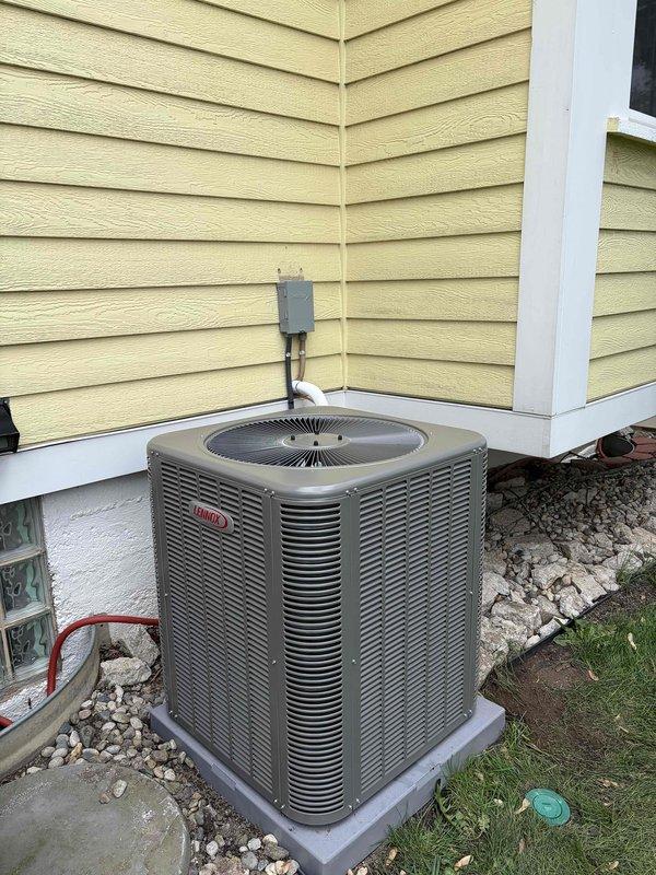 Completed full installation of new air conditioning system including outdoor condensing unit and indoor evaporator coil. Outdoor unit was positioned on concrete pad against house exterior with proper clearance, electrical disconnect mounted on exterior wall, and refrigerant lines run through wall penetration. Indoor evaporator coil was installed above existing furnace in basement mechanical room with new condensate drain line connected to existing drainage system. System was charged with refrigerant, leak tested, and verified for proper operation with all electrical connections completed to code.