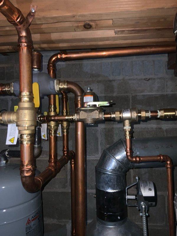 Completed preventive maintenance tune-up on residential hydronic heating system. Performed comprehensive inspection of boiler components, copper distribution piping, zone valves, expansion tank, and pressure relief valve. Verified proper operation of all yellow-handled gas shutoff valves, tested system pressures, checked for leaks at pipe joints and fittings, and confirmed adequate venting through black plastic flue assembly. All components found operating within manufacturer specifications with no deficiencies noted.