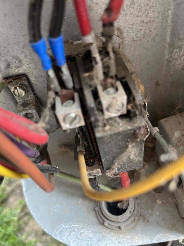 Responded to emergency no-cooling call on thirteen-year-old air conditioning system. Upon inspection, found severely corroded contactor with deteriorated terminals and significant environmental damage affecting electrical connections. Documented existing capacitor and wiring configuration showing multiple compromised connection points due to age and exposure. System components displayed extensive oxidation, grime accumulation, and general wear consistent with unit age, requiring immediate attention to restore cooling operation.