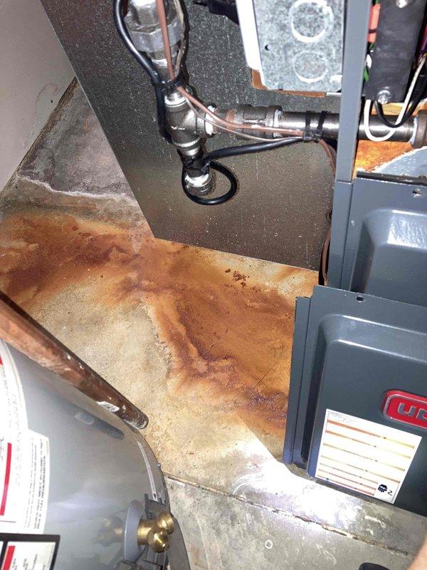 Responded to no heat call and discovered water leaking from furnace. Upon inspection, found extensive rust damage and corrosion to drain pan with standing water accumulation, indicating a clogged condensate drain line. Cleared the blocked condensate drain, removed standing water from base pan, and verified proper drainage flow. Tested system operation to confirm furnace returned to normal heating function with no further water leakage.