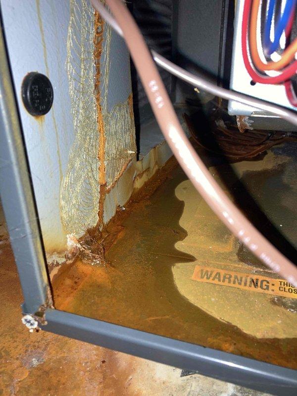Responded to no heat call and discovered water leaking from furnace. Upon inspection, found extensive rust damage and corrosion to drain pan with standing water accumulation, indicating a clogged condensate drain line. Cleared the blocked condensate drain, removed standing water from base pan, and verified proper drainage flow. Tested system operation to confirm furnace returned to normal heating function with no further water leakage.