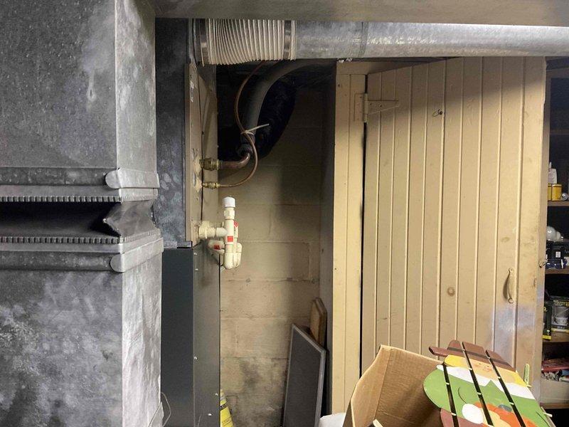 Completed HVAC estimate for Club AC12-2 replacement system in basement utility area. Assessed existing ductwork configuration including circular ventilation ducts, flexible silver ductwork, and corrugated metal conduit throughout exposed ceiling joists. Documented current mechanical installations with copper piping connections, PVC plumbing lines with valve assemblies, and cylindrical HVAC components mounted on concrete block walls. Identified ice formation on overhead piping indicating potential condensation issues and temperature control concerns requiring attention during replacement installation.