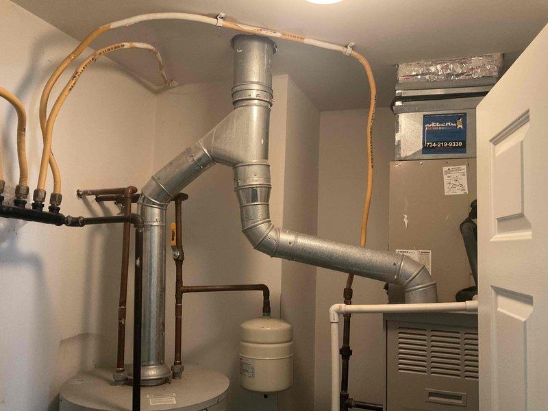 Conducted comprehensive on-site assessment of condominium HVAC system and water heating equipment to provide multiple replacement estimates. Evaluated existing beige HVAC unit with air handler, galvanized ductwork configuration, and white cylindrical water heater with expansion tank in utility room. Documented current equipment specifications, ductwork routing, copper piping connections, and electrical service infrastructure located in exterior concrete alcove between buildings. Photographed existing installations and measured space constraints to develop single component replacement option, full HVAC system replacement quote, and separate water heater replacement proposal for customer consideration.