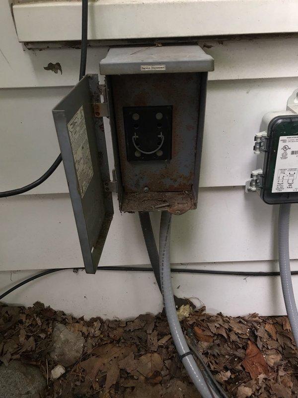 Responded to callback for non-operational air conditioning unit. Upon arrival, performed visual inspection of outdoor condenser unit and associated electrical components. Inspected disconnect box mounted on exterior wall, noting visible rust and corrosion within enclosure that could affect electrical connections and system performance. Evaluated condenser unit positioning, electrical supply routing, and overall installation condition. Documented equipment condition through photographs showing disconnect box interior with corroded components and condenser unit placement on concrete pad. Assessed potential electrical connection issues related to weathered disconnect box that may have contributed to system failure reported by customer.