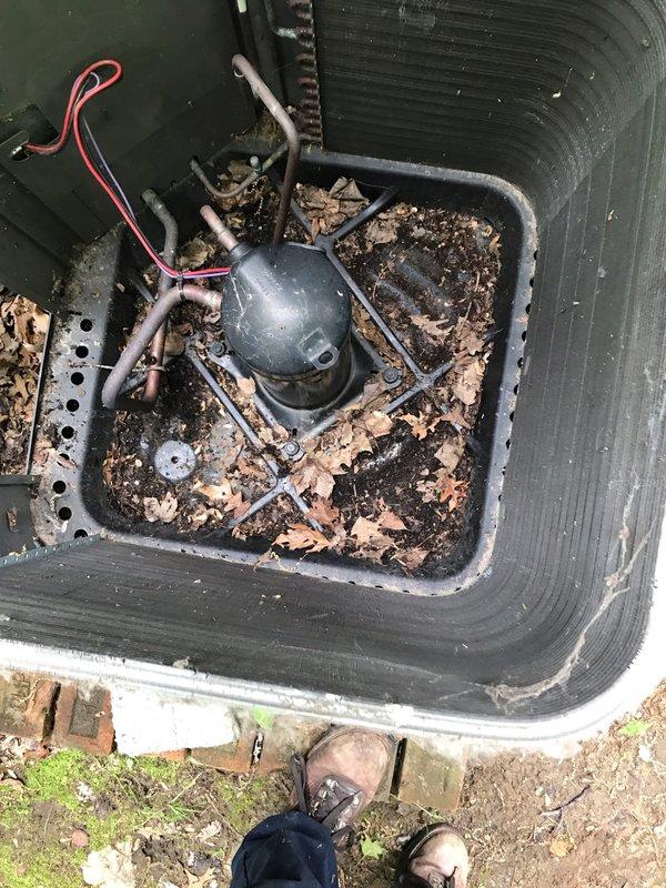 # HVAC Maintenance - Agreement Visit AC&SI

Completed scheduled preventive maintenance visit on residential air conditioning system as part of recurring service agreement. Upon arrival, performed comprehensive inspection of outdoor condensing unit and associated components. 

Noted significant accumulation of organic debris, leaves, and sediment buildup within the condensate drain pan surrounding the compressor assembly. The pan showed evidence of extended exposure with heavy soiling affecting drainage capacity. Inspected compressor unit, refrigerant lines, and electrical connections for proper operation and secure mounting. Verified all copper refrigerant tubing and electrical wiring connections remained intact despite weathered conditions.

Observed deteriorated foam insulation material around the condenser unit base and concrete pad, with fragments scattered on surrounding ground surface. Unit positioned on brick-elevated concrete pad against building exterior with vinyl siding. Con
