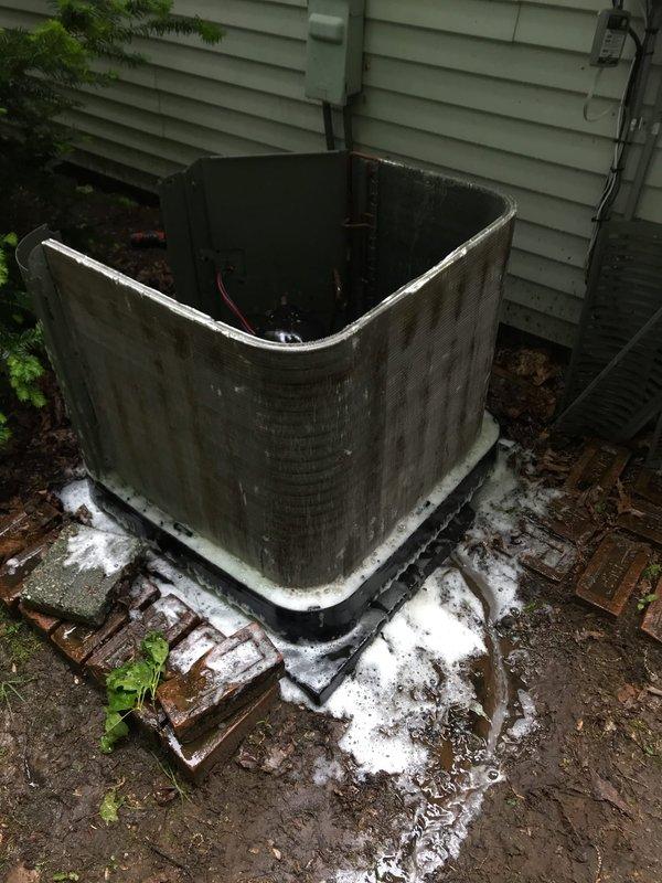 # HVAC Maintenance - Agreement Visit AC&SI

Completed scheduled preventive maintenance visit on residential air conditioning system as part of recurring service agreement. Upon arrival, performed comprehensive inspection of outdoor condensing unit and associated components. 

Noted significant accumulation of organic debris, leaves, and sediment buildup within the condensate drain pan surrounding the compressor assembly. The pan showed evidence of extended exposure with heavy soiling affecting drainage capacity. Inspected compressor unit, refrigerant lines, and electrical connections for proper operation and secure mounting. Verified all copper refrigerant tubing and electrical wiring connections remained intact despite weathered conditions.

Observed deteriorated foam insulation material around the condenser unit base and concrete pad, with fragments scattered on surrounding ground surface. Unit positioned on brick-elevated concrete pad against building exterior with vinyl siding. Con