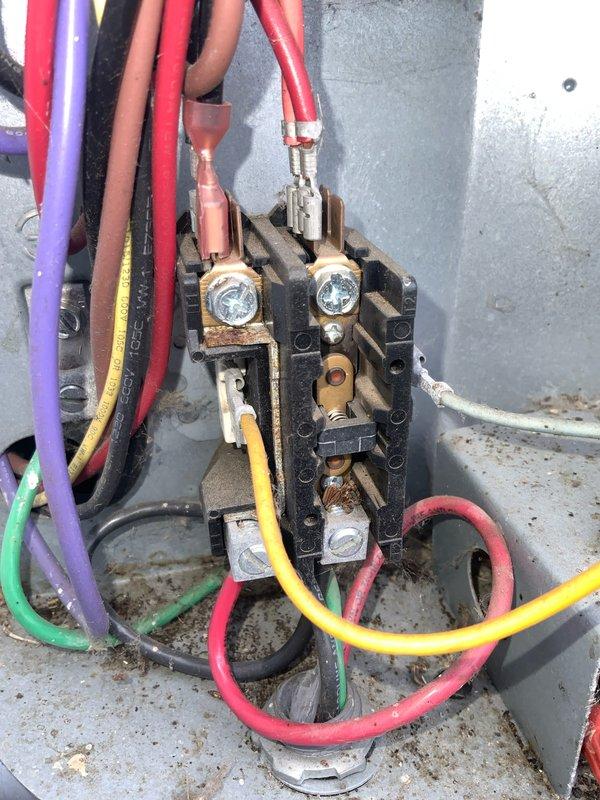Performed routine maintenance agreement visit on air conditioning system. Inspected blower wheel assembly, noting normal dust accumulation on fan blades and center plate. Examined electrical terminal block and contactor, observing significant corrosion and rust on brass terminals and mounting hardware indicating exposure to moisture over time. All colored control wiring connections were verified secure despite age-related deterioration of components.