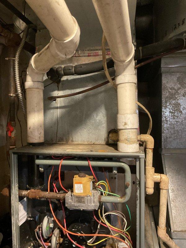 Conducted comprehensive assessment and provided estimate for complete HVAC system replacement. Evaluated existing furnace and air handler installation, including gas valve assembly, control wiring, and condensate drainage system. Documentation captured current equipment condition showing aged PVC condensate lines with accumulated wear, exposed control components with multi-wire connections to gas valve, and mixed piping infrastructure combining PVC and copper materials in basement utility space.