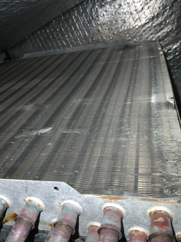 Completed preventive maintenance tune-up on air conditioning system over 10 tons. Inspected blower assembly and evaporator coil, noting dust accumulation on coil fins and minor rust discoloration on refrigerant line connections. Documented equipment condition with photographs for service records.