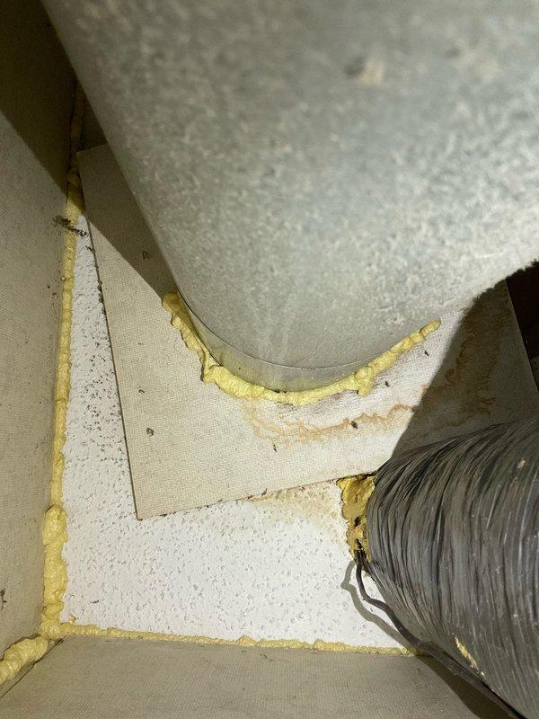 Completed comprehensive HVAC system replacement estimate for residential property, documenting existing furnace configuration including gas valve assembly, flexible gas line connections, and ductwork routing through confined utility space. Photographed current equipment conditions showing insulated ductwork with foam sealing at wall penetrations and interior furnace compartment components to support replacement specifications and system design requirements.