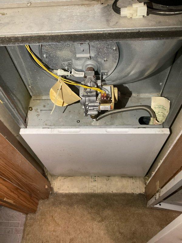 Completed comprehensive HVAC system replacement estimate for residential property, documenting existing furnace configuration including gas valve assembly, flexible gas line connections, and ductwork routing through confined utility space. Photographed current equipment conditions showing insulated ductwork with foam sealing at wall penetrations and interior furnace compartment components to support replacement specifications and system design requirements.