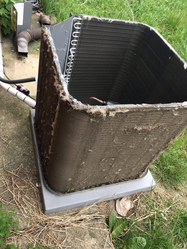 Responded to service call for rattling noise in refrigerant line between outdoor condenser unit and indoor air handler. Upon arrival, performed visual inspection of outdoor unit and associated piping. Removed access panel from condenser to examine internal components and verify proper operation. Inspected refrigerant lines, insulation wrapping, and mounting hardware for loose connections or deterioration that could cause vibration noise. Checked condenser coil condition and noted heavy dirt accumulation on exterior panels and unit housing. Documented equipment condition with photographs showing weathered cabinet, environmental wear, and debris buildup around unit perimeter. Verified electrical disconnect box connections and examined all visible piping runs for secure mounting and proper support. Unit operational at time of inspection with cooling cycle functioning.