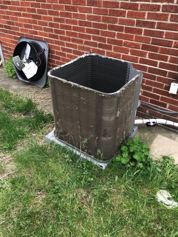 Responded to service call for rattling noise in refrigerant line between outdoor condenser unit and indoor air handler. Upon arrival, performed visual inspection of outdoor unit and associated piping. Removed access panel from condenser to examine internal components and verify proper operation. Inspected refrigerant lines, insulation wrapping, and mounting hardware for loose connections or deterioration that could cause vibration noise. Checked condenser coil condition and noted heavy dirt accumulation on exterior panels and unit housing. Documented equipment condition with photographs showing weathered cabinet, environmental wear, and debris buildup around unit perimeter. Verified electrical disconnect box connections and examined all visible piping runs for secure mounting and proper support. Unit operational at time of inspection with cooling cycle functioning.
