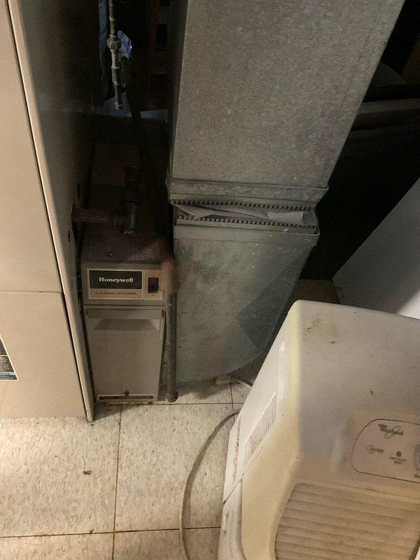 Completed comprehensive estimate for complete HVAC system replacement in residential utility room. Assessed existing furnace unit with associated ductwork, plenum configuration, and thermostat control system. Documented current installation including sheet metal ductwork transitions, existing PVC condensate drainage lines, electrical disconnect box, and copper refrigerant lines for replacement planning purposes.