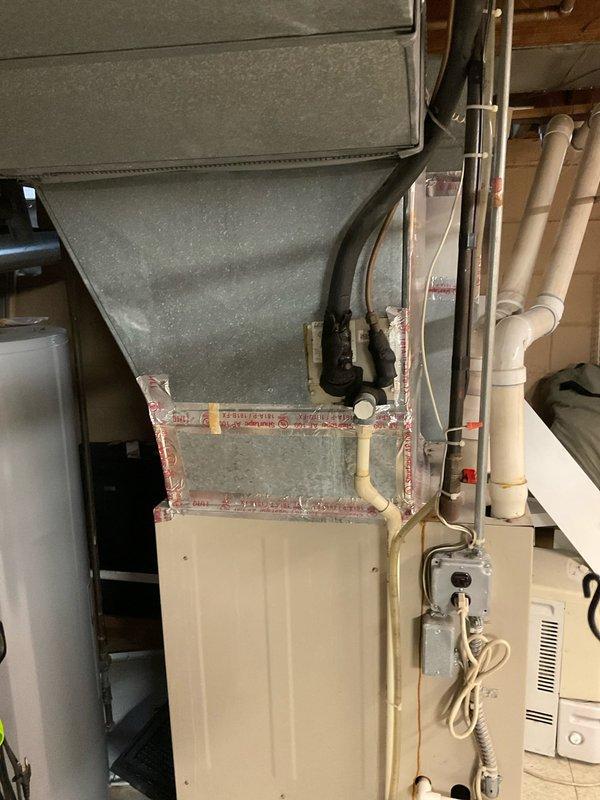 Completed comprehensive estimate for complete HVAC system replacement in residential utility room. Assessed existing furnace unit with associated ductwork, plenum configuration, and thermostat control system. Documented current installation including sheet metal ductwork transitions, existing PVC condensate drainage lines, electrical disconnect box, and copper refrigerant lines for replacement planning purposes.