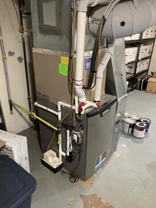 Responded to emergency no-cooling call for new homeowner with system age unknown. Upon arrival, performed diagnostic evaluation of split HVAC system including indoor furnace unit in basement mechanical room and outdoor condensing unit. Outdoor condenser showed signs of age and weathering with visible discoloration on housing. Inspected electrical connections at exterior disconnect box, refrigerant lines, and condensate drainage system. Evaluated indoor air handler connections, ductwork interface, and electrical components. System components included gas furnace with PVC venting, expansion tank, and standard residential cooling equipment. Documented equipment condition through photographic records for homeowner reference and future service history.