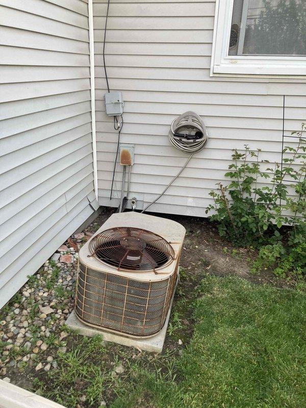 Responded to emergency no-cooling call for new homeowner with system age unknown. Upon arrival, performed diagnostic evaluation of split HVAC system including indoor furnace unit in basement mechanical room and outdoor condensing unit. Outdoor condenser showed signs of age and weathering with visible discoloration on housing. Inspected electrical connections at exterior disconnect box, refrigerant lines, and condensate drainage system. Evaluated indoor air handler connections, ductwork interface, and electrical components. System components included gas furnace with PVC venting, expansion tank, and standard residential cooling equipment. Documented equipment condition through photographic records for homeowner reference and future service history.