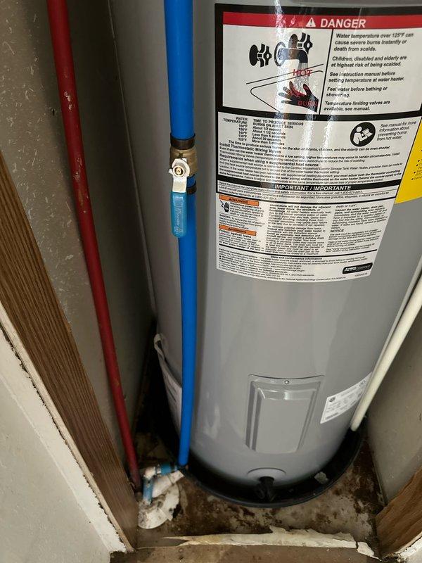Completed installation of new tanked water heater in residential utility closet. Removed existing unit and installed replacement water heater with proper hot and cold water line connections using color-coded piping (red for hot, blue for cold supply). Ensured all connections were secure with appropriate valves and fittings, verified proper placement on concrete pad, and confirmed all safety labels and warnings were visible and intact per manufacturer specifications. Unit tested and operational upon completion.