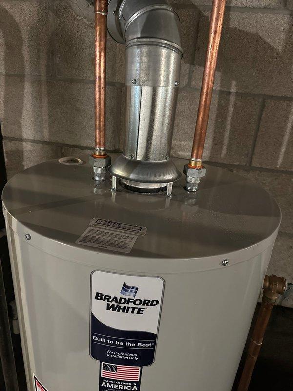Completed installation of new Bradford White tanked water heater in basement utility area. Removed existing unit and positioned new water heater on platform per manufacturer specifications. Connected hot and cold water supply lines using copper piping with proper compression fittings. Installed galvanized metal flue vent pipe with 90-degree elbow configuration for proper exhaust ventilation. Verified all connections for proper seal and tested unit operation to ensure functionality. Installation meets professional standards with clean piping runs and secure mounting. Service financed and documentation on file.