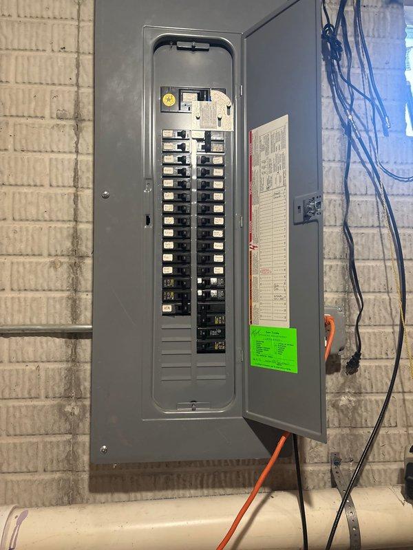 Installed high voltage electrical line from main service panel to exterior outlet location. Ran new electrical conduit through basement utility area, routing orange-jacketed high voltage cable from breaker panel through cinder block wall penetration to outdoor mounting point on brick exterior. Added new circuit breaker to existing electrical panel and terminated connections per code requirements. Installed exterior weatherproof outlet box on brick facade with proper conduit protection and secure mounting hardware. Verified all connections, tested circuit functionality, and ensured proper grounding throughout the installation.