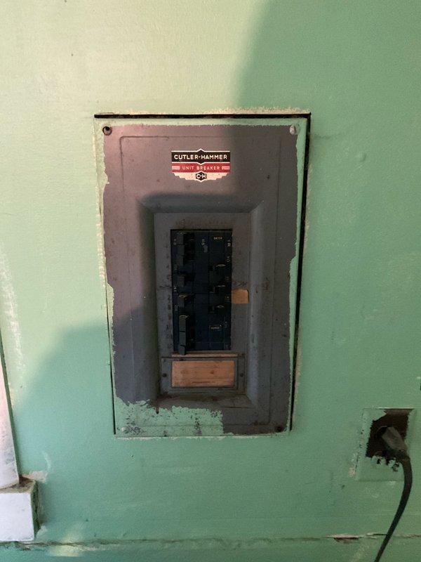 Performed on-site evaluation for HVAC system replacement estimate. Assessed existing electrical infrastructure, documenting vintage Pushmatic Electri-Center breaker panel and secondary Cutler Hammer panel installation. Both panels exhibited age-related wear and are recessed into light green painted walls with visible deterioration around mounting frames. Photographed electrical service configuration to determine compatibility requirements for proposed HVAC equipment installation. Evaluated available circuit capacity and panel conditions to ensure adequate power supply for new system components. Documentation completed for comprehensive system replacement proposal including electrical upgrade considerations necessary for modern HVAC equipment integration.