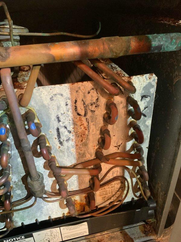 Responded to no cooling complaint on 33-year-old air conditioning system. Upon inspection, found severely corroded evaporator coil with significant oxidation, rust staining, and verdigris formation throughout copper tubing and heating elements. Condenser fan motor and blades showed heavy dust accumulation and aging. Documented extensive deterioration of internal components with photographic evidence. Given the advanced age and severe corrosion of critical components, recommended system replacement as most cost-effective solution, as repair costs would likely exceed value of aging equipment and efficiency improvements from new system would provide substantial energy savings.