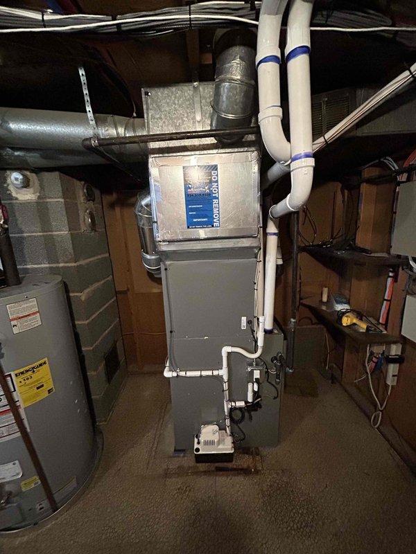 Completed full HVAC system installation in basement mechanical room, including 70,000 BTU gas furnace, 2-ton air conditioning unit with rear discharge configuration, and whole-home humidifier. Installed all mechanical components, electrical connections, and ductwork transitions. Routed PVC condensate drainage lines with proper support strapping to ceiling joists. Mounted condensate pump on platform at furnace base. Connected refrigerant lines and verified proper system operation. All equipment secured per manufacturer specifications with appropriate clearances maintained for service access. System tested and operational upon completion.