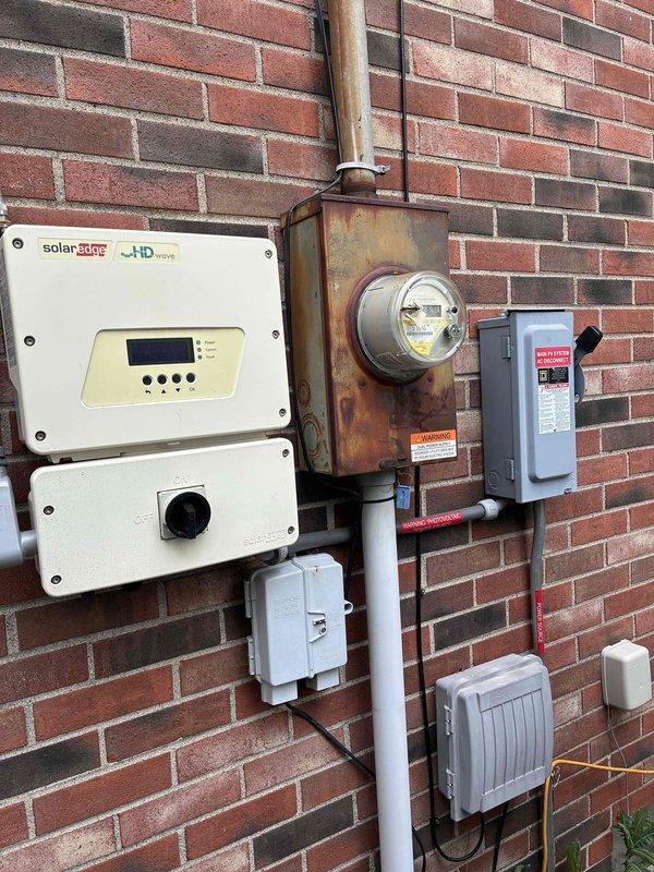 Conducted comprehensive site evaluation for HVAC system replacement at residential property. Documented existing exterior utility infrastructure including gas meter assembly, electrical service panel with solar inverter integration, and available mounting locations along brick exterior wall. Assessment confirmed adequate clearances and utility access points for proposed 4-6 ton system installation, noting existing electrical service configuration and gas line routing for equipment placement planning.