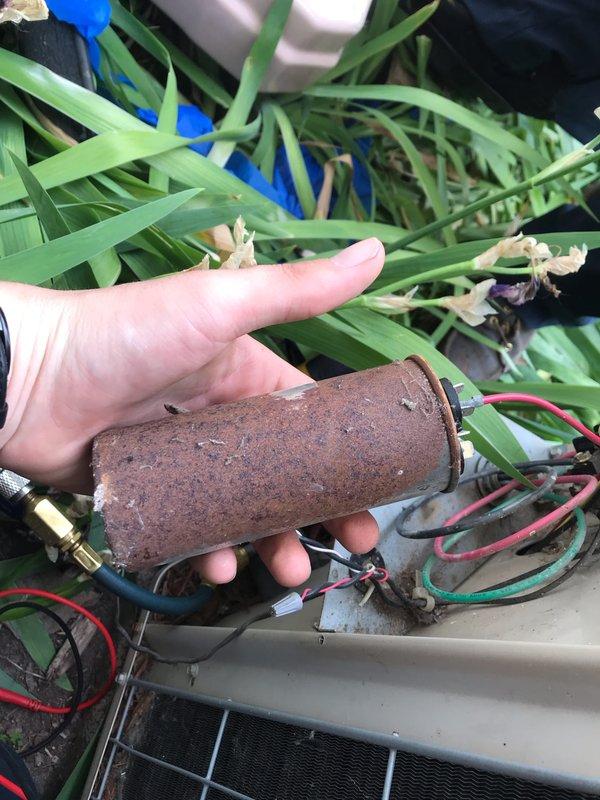 # No Cool Service Call - 20-Year-Old AC Unit

Responded to a no cooling complaint on a 20-year-old outdoor air conditioning system. Upon arrival, customer reported the unit was still operating but not producing adequate cold air. 

Performed visual inspection of the outdoor condensing unit and removed the top access panel to examine internal components. Found extensive corrosion and deterioration throughout the electrical compartment, with visible rust on metal surfaces and discoloration indicating prolonged exposure to the elements.

Inspected the filter drier canister and discovered severe corrosion across the entire component. The cylindrical metal housing exhibited heavy rust penetration with a rough, degraded surface texture, compromising the integrity of the refrigeration system. The extensive corrosion on the filter drier indicated long-term moisture contamination within the sealed refrigeration circuit.

Documented the condition of electrical wiring, capacitor, and internal com
