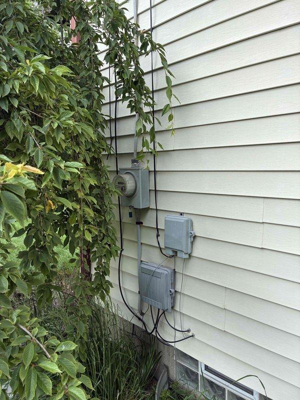 Conducted on-site evaluation of existing outdoor air conditioning condenser unit located in confined side yard area between structures. Assessed current equipment condition, electrical disconnect configuration, and meter placement for replacement feasibility. Documented unit positioning on concrete pad, clearance constraints imposed by brick wall, vinyl siding, and wooden fence, along with existing electrical conduit routing from distribution boxes to support comprehensive replacement estimate.