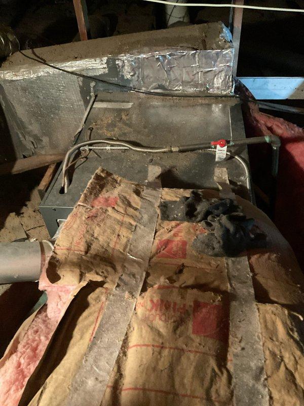 Conducted comprehensive HVAC system assessment in attic space for air conditioning replacement estimate. Evaluated existing ductwork assembly showing significant age and wear, with deteriorated fiberglass insulation exhibiting compression, discoloration, and substantial degradation requiring replacement consideration. Documented current system conditions including metal ductwork with reflective foil covering, PVC drain line connections, electrical junction box placement, and flexible conduit routing to provide accurate equipment replacement specifications and identify necessary ancillary work for complete system installation.
