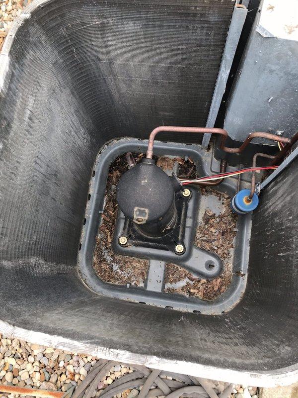 Completed preventive maintenance inspection on residential air conditioning system as part of CLUB AC 8-12 agreement. Performed comprehensive visual assessment of outdoor condensing unit, noting significant accumulation of dirt, biological growth, and organic debris around compressor and within installation area. Documented equipment condition through photographic records showing weathered exterior casing with mold and mildew buildup on surfaces, dried leaves and plant matter collected around base components, and general outdoor exposure deterioration. Inspected copper refrigerant lines, electrical connections, compressor mounting, and drain pan placement. Unit operational at time of service with all components functioning within normal parameters despite cosmetic weathering from extended outdoor exposure.