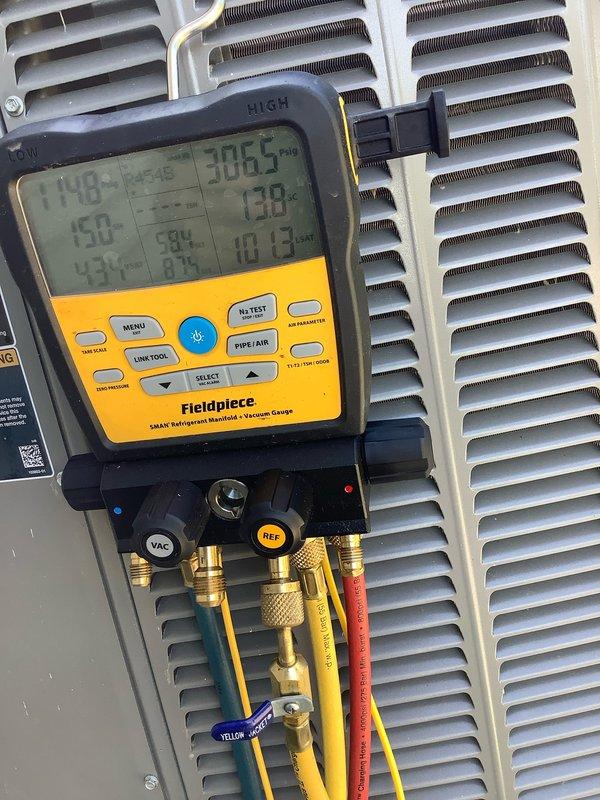 # HVAC Maintenance Visit - Ice Buildup on Outdoor Coil

Responded to service call for ice accumulation on outdoor condenser coil. Upon arrival, found AC&SI unit with significantly restricted airflow due to heavily clogged condenser coils. External coil surfaces showed substantial debris buildup consisting of dirt, dust, and organic material that was impeding proper heat transfer and causing abnormal ice formation.

Connected Fieldpiece SMAN digital manifold gauges to service ports to assess system pressures and temperatures. Initial diagnostics revealed operating conditions consistent with restricted airflow across condenser. Temperature readings displayed 306.5°F and 13.8°F at respective measurement points, indicating system imbalance.

Performed thorough cleaning of condenser coils to remove accumulated debris and restore proper airflow. Cleared both intake and discharge sides of coil assembly to ensure unrestricted air circulation. Unit was positioned on concrete pad with gravel sur