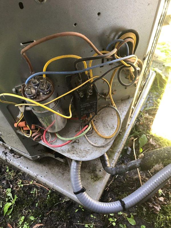 # AC No Cool - Loud Noise Complaint

Responded to service call for air conditioning unit making loud noise. Upon arrival, performed visual inspection of outdoor condensing unit which revealed system is 10+ years old with significant neglect and environmental exposure. Unit showed heavy accumulation of dirt, dust, debris, and spider webs throughout electrical compartment and internal components.

Inspected electrical connections and found multiple wires with signs of weathering and age-related deterioration. Capacitor showed visible corrosion and surface rust, indicating potential electrical component failure. Contactor assembly exhibited dirt buildup and environmental contamination. All wiring connections were checked for tightness and integrity.

Unit is located at ground level on weathered concrete pad with vegetation growth encroaching on equipment. Concrete pad showed moss and algae growth, indicating drainage issues and prolonged moisture exposure affecting equipment longevity.

B