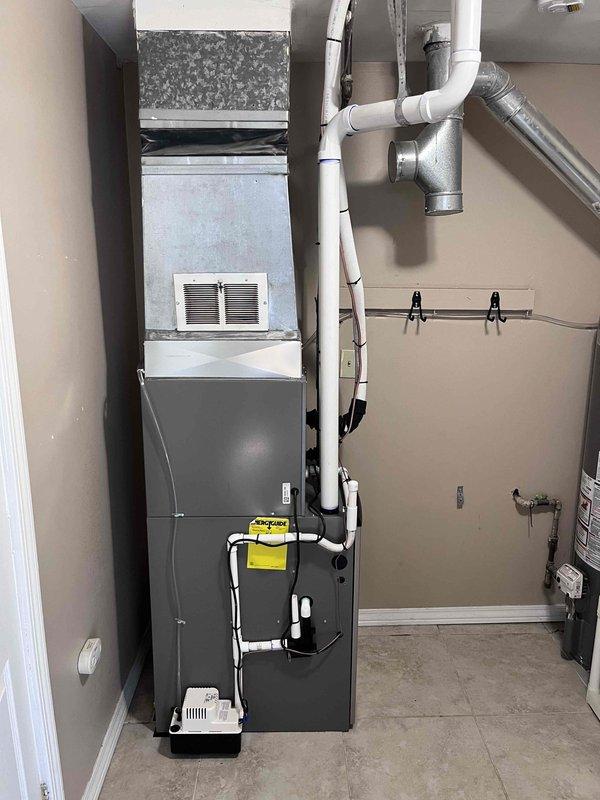 Successfully completed installation of a complete HVAC system consisting of a 70,000 BTU furnace and 2-ton air conditioning unit in rear utility area. Installed new furnace with proper venting using white PVC piping secured with mounting brackets, established condensate drainage system with drain pan at base of unit, and connected all ductwork including metallic flexible ducts and air handler components. Completed all mechanical and electrical connections, reconnected system to existing infrastructure, and verified proper operation of all equipment. All necessary permits processed and installation meets code requirements.
