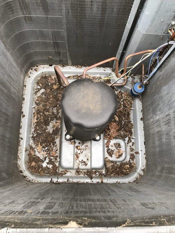 # HVAC Service Completed

Responded to a no-cooling complaint on a 2-year-old residential air conditioning system. Upon arrival, found the outdoor condenser unit heavily covered with dirt, grime, mold, and organic growth, with surrounding vegetation encroaching on the equipment. The unit's exterior surfaces showed extensive contamination that was restricting proper airflow through the condenser coil.

Performed comprehensive cleaning of the condenser unit, removing accumulated debris, organic matter, and biological growth from all exterior surfaces and coil fins. Cleared vegetation and debris from around the unit perimeter to restore proper clearance for adequate airflow. Inspected internal components and found copper refrigerant lines intact with no visible damage. Noted significant weathering and rust accumulation on the base pan and mounting surfaces, though structural integrity remained sound.

After cleaning, verified system operation with normal airflow through the condenser coil