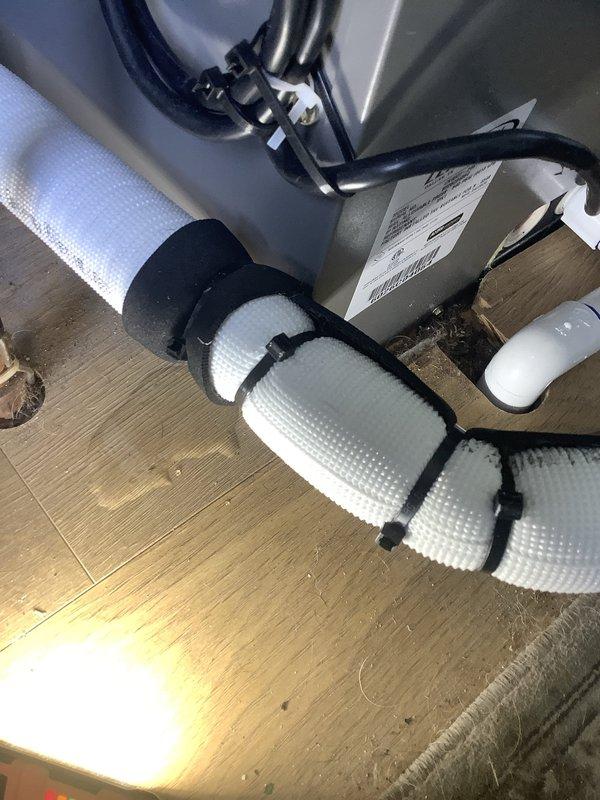 Responded to callback for possible refrigerant leak at evaporator coil. Inspected refrigerant line connections and coil assembly, documented insulated linesets and condensate drain configuration with securing straps. Visual inspection completed of mechanical connections and pipe joints at unit base to identify source of reported leak.