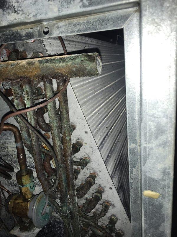 Responded to no cooling complaint on residential air conditioning system. Upon inspection, found heavily corroded evaporator coil with extensive oxidation and deterioration affecting heat transfer efficiency, causing unit to blow warm air. Contactor assembly showed signs of age but remained operational. Documented coil condition and advised replacement due to severity of corrosion compromising system performance.