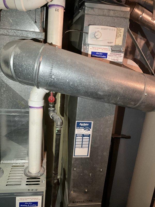 Conducted on-site assessment of existing HVAC system for air conditioning replacement estimate. Evaluated current furnace installation with Aprilaire humidification system, inspected ductwork condition and routing, and documented mechanical room configuration including PVC condensate drainage, copper refrigerant lines, and existing control systems. Photographed equipment layout and spatial constraints to develop accurate replacement proposal for new air conditioning unit compatible with current infrastructure.