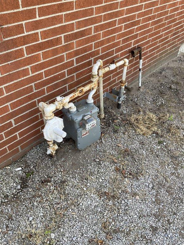 Conducted on-site assessment for single zone mini split air conditioning system installation in office space. Evaluated exterior wall conditions, existing utility locations including gas meter placement, and potential mounting locations for outdoor condenser unit. Documented gravel pad area and building exterior with horizontal siding for equipment placement considerations. Assessed electrical requirements and condensate drainage options to provide comprehensive installation estimate.
