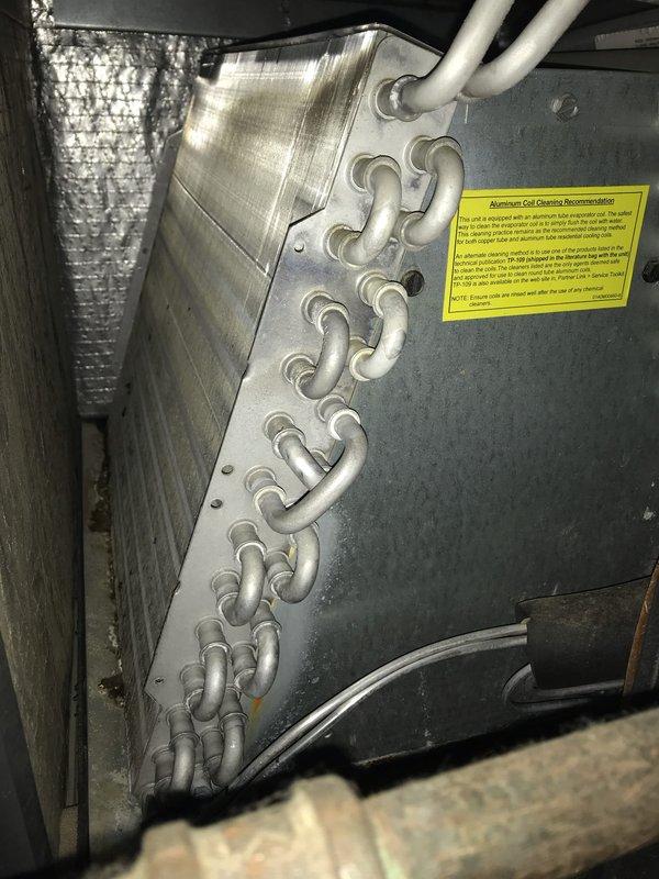 Responded to service call for uneven heating and cooling in home with 50-year-old HVAC system and original ductwork installed in slab. Performed comprehensive inspection of ductwork system to assess condition and identify potential causes of temperature inconsistencies throughout the residence. Inspected evaporator coil unit in attic space, noting clean copper refrigerant tubes and operational components, with aluminum coil cleaning recommendation label visible on unit. Assessed flexible ductwork insulation and overall system condition. Completed four-hour diagnostic inspection to evaluate aging duct system and provide recommendations for addressing uneven temperature distribution issues.