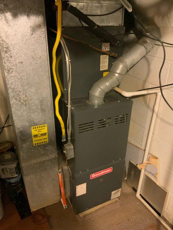 # HVAC Service Report

Responded to no cooling complaint on 10+ year old Goodman air conditioning system. Customer reported unit blowing air but not producing cold air and suspected low refrigerant charge. Upon arrival, performed comprehensive system diagnostic on outdoor condenser unit and indoor air handler/furnace combination.

Conducted visual inspection of outdoor condensing unit located in narrow side yard service area. Checked electrical disconnect, verified power supply, and inspected condenser coil condition. Unit showed age-related wear consistent with 10+ year old equipment. Examined indoor air handler components in basement utility area, including evaporator coil access, refrigerant line connections, and airflow pathways.

Performed refrigerant pressure testing on both high and low side service ports to determine system charge level. Confirmed refrigerant deficiency indicated by abnormal pressure readings and lack of cooling capacity. Conducted leak detection procedures usi