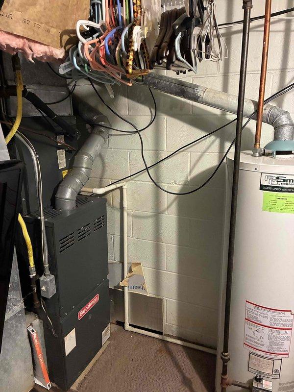Responded to service call for 25+ year old Goodman air conditioning system experiencing compressor failure. Diagnosed compressor shorted to ground, causing main house circuit breaker to trip repeatedly. Documented existing HVAC equipment configuration in basement utility area, including furnace, water heater, electrical panel, and ductwork layout. Provided replacement estimate for complete AC system due to age of equipment and critical component failure, noting urgent need for air conditioning restoration.