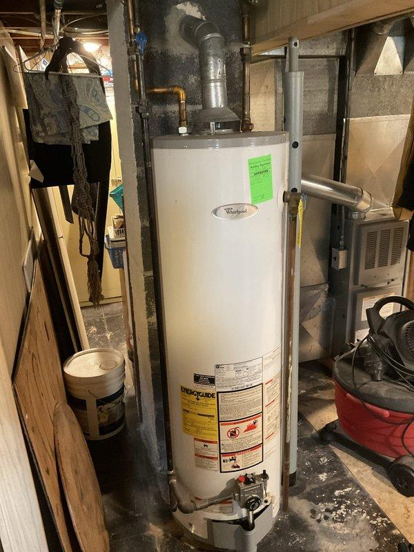 Provided estimate for replacement of non-functional 18-year-old standard water heater in single-family home basement. Assessed existing Whirlpool unit with natural draft venting configuration and documented current installation including copper supply connections, overhead piping, and vertical vent stack. Evaluated basement utility space conditions and confirmed requirements for standard tank-type water heater replacement.