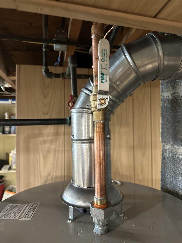 Installed Bradford White tanked water heater in basement utility area, completing mechanical connections only. Connected copper water supply lines to unit inlet and outlet, installed temperature and pressure relief valve with copper discharge pipe, and reconnected existing ventilation ductwork at 45-degree angle for proper exhaust. All plumbing connections tested and verified operational, with unit positioned on concrete floor per manufacturer specifications.