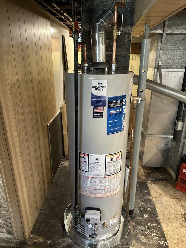 Installed Bradford White tanked water heater in basement utility area, completing mechanical connections only. Connected copper water supply lines to unit inlet and outlet, installed temperature and pressure relief valve with copper discharge pipe, and reconnected existing ventilation ductwork at 45-degree angle for proper exhaust. All plumbing connections tested and verified operational, with unit positioned on concrete floor per manufacturer specifications.