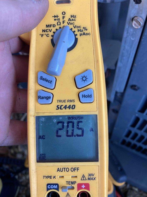 Performed routine maintenance inspection on air conditioning system as part of club preventative maintenance agreement. Utilized digital multimeter to verify electrical measurements, recording 20.5 amp inrush current and 0.52 amp operating current with proper voltage readings, confirming compressor and system components operating within normal parameters.