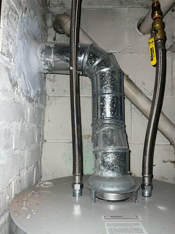 Completed club membership preventive maintenance visit on air conditioning system and water heater unit model WA6036WHA1A. Performed comprehensive inspection of HVAC equipment including visual assessment of water heater installation, verified proper operation of gas shut-off valve, examined condition of galvanized exhaust vent piping with elbow joint, and inspected flexible stainless steel braided water supply connections. Documented equipment condition through photographic records showing functional residential mechanical systems in basement utility area with all components operating within normal parameters.